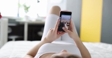 Kadın yatakta uzanıyor ve dinlenme telefonundaki fotoğraflara bakıyor. Uykusuzluk ve seyahat konseptinden hatıralar
