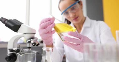 Koruyucu gözlüklü doktor laboratuarda sarı bir sıvıyla test tüpü tutuyor. Laboratuvar teşhisi yağ araştırma konsepti
