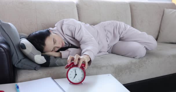 眠っている怠惰な女性はソファに横たわって リンギング目覚まし時計をオフにします 昼間の眠気やうつ病の概念 — ストック動画