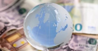 Cam küre farklı ülkelerin parasının üzerinde duruyor. Dünya ekonomisi kavramı