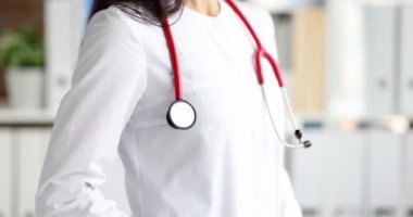 Beyaz önlüklü kadın doktor kameraya dönüyor. Doktorluk konseptinin en yüksek ücretli uzmanlığı