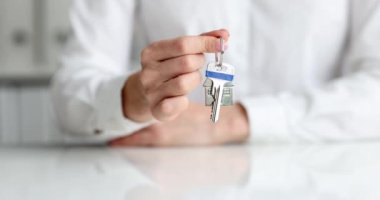 Kadın ajan alışveriş yaptıktan sonra anahtarlıkla evin anahtarlarını uzatıyor. Gayrimenkul satın alma kavramı