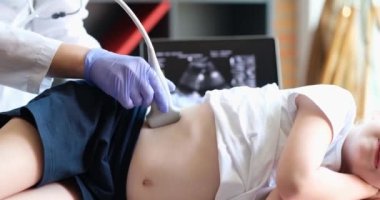 Ultrason cihazı kullanan küçük bir kızın tıbbi muayenesi. Sonograf çocuk karnındaki ve böbreklerindeki güç çeviriciyi hareket ettiriyor. Profesyonel klinik tanılama ve tedavi