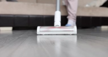 Kadın kablosuz elektrik süpürgesini kaplamaları temizlemek için kullanıyor. Temizlik hizmetleri kavramı