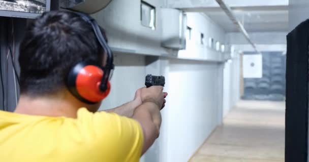 男性枪手手持手枪向目标射击的后视镜 武器训练射击场 — 图库视频影像