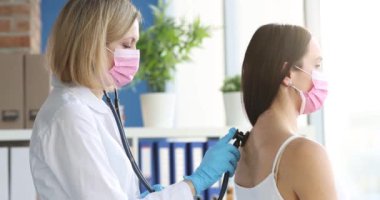 Terapist, koruyucu maskeli hastaların ciğerlerini dinler. Zatürree gribi ve covid-19 konsepti