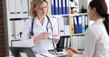 Doktor meme bezlerini büyütmek için hastanın silikon göğüs implantlarını gösteriyor. Estetik ameliyat konsepti