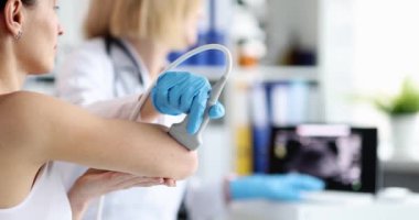 Doktor, hastanın dirsek eklemini ultrasonla muayene ediyor. Dirsek eklemindeki ağrı teşhis ve tedavi konseptine neden olur.
