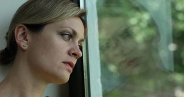 Üzgün, yorgun kadın pencereden yakından bakıyor. Yalnız kadın depresyonda.