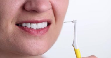 Kadın diş fırçasıyla ya da özel olarak diş içi boşlukları temizlemek için tasarlanmış küçük fırçayla tutuyor. Diş etlerini ve dişlerini sağlıklı tutmanın etkili bir yolu.