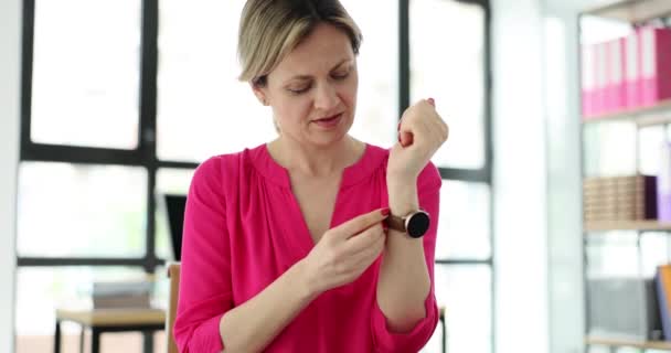 美しい女性はオフィスで手にスタイリッシュな手首の腕時計を置きます 女性の腕時計の選択 — ストック動画