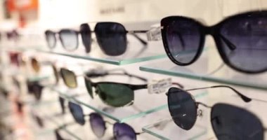 Mağazadaki raflarda moda güneş gözlükleri var. Kaliteli güneş gözlüğü seçimi