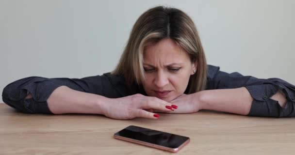 외로운 소녀는 식탁에 전화를 기다리고 여자가 스마트폰에서 전화나 메시지를 기다리고 — 비디오
