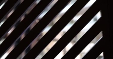 Güneş, pencere perdeleri boyunca parlar. Güneş ahşap parmaklıkları delip geçer