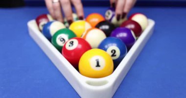 Oyuncu, bilardo toplarını masa numaralarıyla üçgen raflarda topluyor. Bilardo oyunu