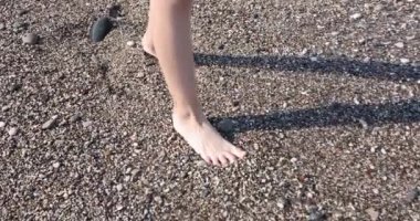 Çocukların ayakları kayalık sahilden suya girer. Deniz konseptinde tatil