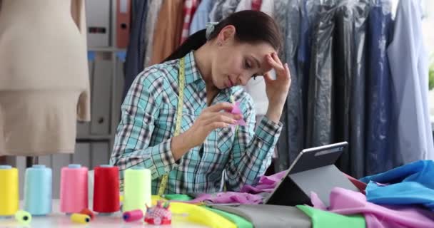 Κουρασμένη Βαριεστημένη Ράφτρα Βελονάκι Επιλέγει Υλικά Σχεδιαστικά Ρούχα Στο Τραπέζι — Αρχείο Βίντεο