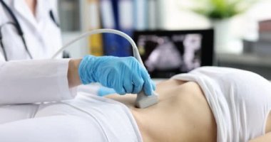 Ultrason tarayıcı uzman doktorun elinde. Hamileliğin ilk dönemlerinde hastayı muayene ediyor. Karın ultrasonu yapan hasta.