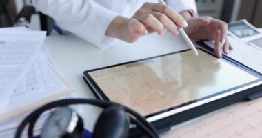 Doktor, klinikte elektrokardiyogramla tablet tutuyor. Kalp ritim bozukluğu ve kalp tedavisi konsepti.
