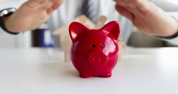 保険代理店は家族と豚の銀行に手を置いています — ストック動画
