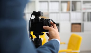 Takım elbiseli erkek silah kamera tripod promo videoblog veya fotoğraf oturumu ofis portre yapmak için mount. Vlogger küme ayarlama ve iş teklif promosyon selfie bilgileri göstermek için görüntü kalitesini kontrol edin