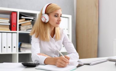 Güzel kız öğrencinin öğrenme ve müzik kulaklık ile. Elini ve kameraya bakarak ağılda tutun