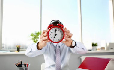 Alarm saati bir kırmızı renk erkek el ofiste 7 oclock sabah veya akşam Am am gösteren tablo üzerinde durur.