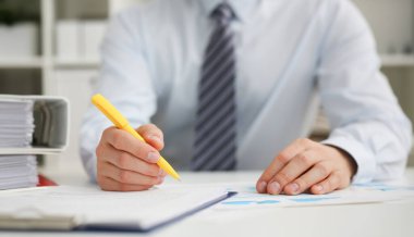 Sarı kalem açılan Not Defteri sayfasına Not yapmaya hazır tutan erkek el. Çalışma alanı, takım elbiseli işadamı yapmak düşünceler kayıtları özel tertipçi beyaz yakalı konferans imza kavramı