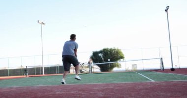 Tennis player hits ball on outdoor tennis court. Tennis game