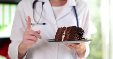 Nutritionist doctor holds piece of cake and warns about dangers of sweets. Sugar benefits and harms to human health