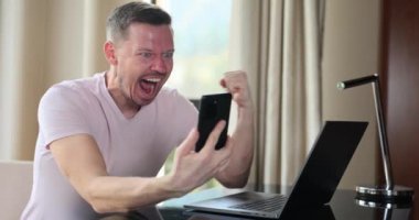 Happy man looking at phone screen and celebrating online victory. Emotions of financial monetary success and successful business contract