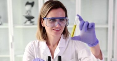 Quality control in of oil refining industry. Woman chemist holding test tube with yellow liquid biological research closeup