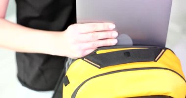 Woman puts laptop in sports backpack. Transportation of computer equipment while traveling
