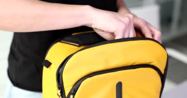 Woman hand puts one hundred dollar American bills in backpack. Travel cash