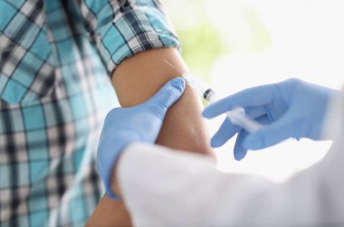 Doktor hastaya omzundan iğne yapıyor. Nüfusun bulaşıcı hastalıklara karşı aşılanması kavramı