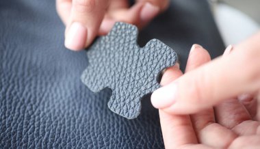 Koyu mavi deri örneğini yakından tutan kadın eli. Deri ürünlerinin kalitesi