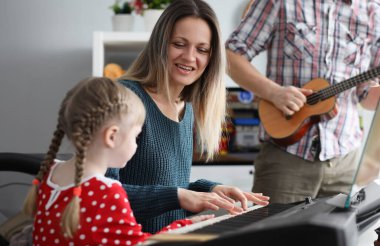 Kadın ve erkek küçük kıza müzik aleti çalmayı öğretiyor. Aile eğlence konsepti