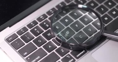 Büyüteç bilgisayar klavyesinde yatıyor. İnternet konsepti hakkında bilgi araması