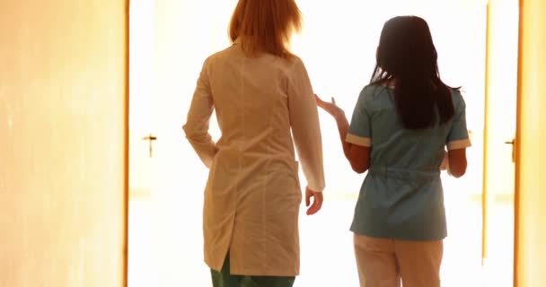 Twee Vrouwelijke Dokters Lopen Door Gang Praten — Stockvideo