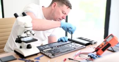 Usta tamirci atölyede dizüstü bilgisayarı tamir ederken tornavida 4K film yavaş çekimde. Garanti konsepti altında elektronik ürünlerin bakımı