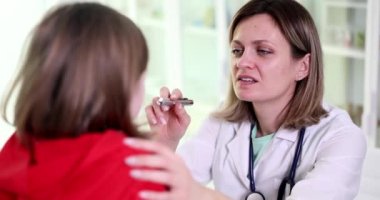 Doktor çocuk doktoru, el feneri 4K filmli ağır çekimle çocuğun boğazını inceliyor. Çocuk konseptinde akut mevsimsel solunum hastalıklarının teşhisi ve tedavisi