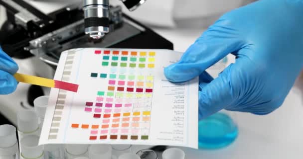 Kemisti Vertaamalla Värillisiä Litmuspaperia Värinäytteisiin Laboratoriossa Lähikuva Elokuva Hidastettuna Kemiallisten — kuvapankkivideo