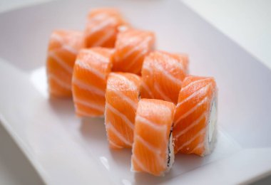 Delicious philadelphia masago rolls on white plate. Sushi rolls with salmon cucumber and cheese and japanese food concept