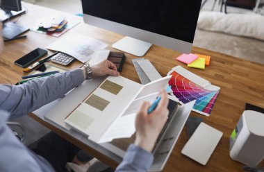 Close-up of interior designer create color mix for new house project, palette on workplace in agency. Samples with options on desk. Creativity, art concept