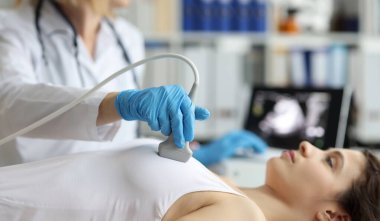 Portrait of doctor makes woman breast ultrasound, treatment before breast augmentation, full checkup in clinic. Womans health, medicine, hospital concept