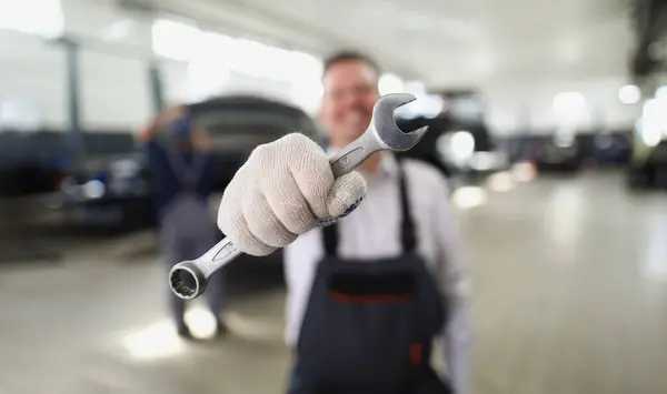 Close-up of service worker hold wrench equipment, metal tool to fix vehicle. Provide high quality machine service on station. Pit stop, maintenance concept