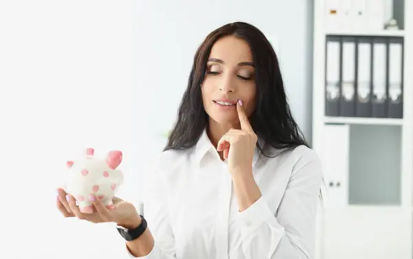 Portrait of woman hold piggybank, think of better way to use money, saving up for future. Female saving for shopping. Investment, saveup, finance concept