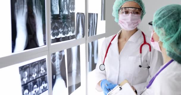 Vrouwelijke Artsen Beschermende Maskers Glazen Kijken Naar Röntgenfoto Kliniek Film — Stockvideo