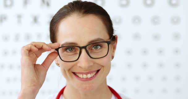 Γυναίκα Οφθαλμίατρος Γιατρός Απογειώνει Γυαλιά Στο Φόντο Του Πίνακα Της — Αρχείο Βίντεο