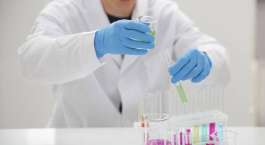 Bir erkek kimyager tüp elinde cam taşmaları potasyum permanganat yürüten bir analiz tepki alır çeşitli sıvı bir çözüm tutan kimyasal üretim kullanarak reaktifler sürümleri.